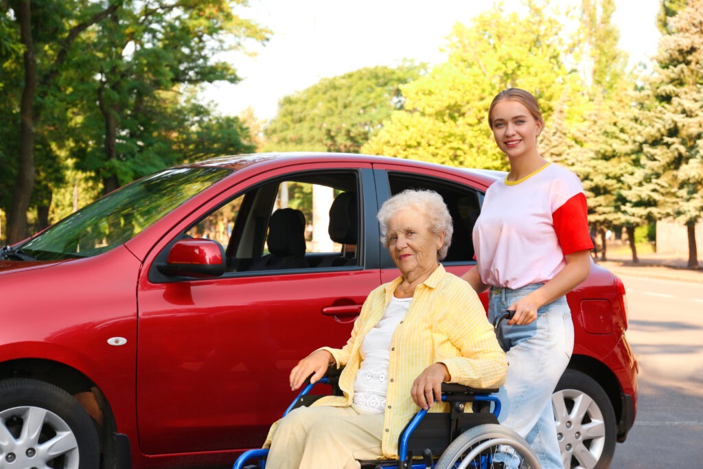A senior disabled woman being assisted outdoors, highlighting accessible travel support from holiday companies for disabled people at Accessible Travelling.