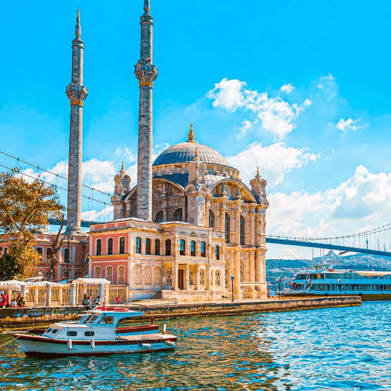 Ortaköy Mosque stands majestically by the Bosphorus, framed by sunny skies and boats. The iconic structure showcases Ottoman architecture.